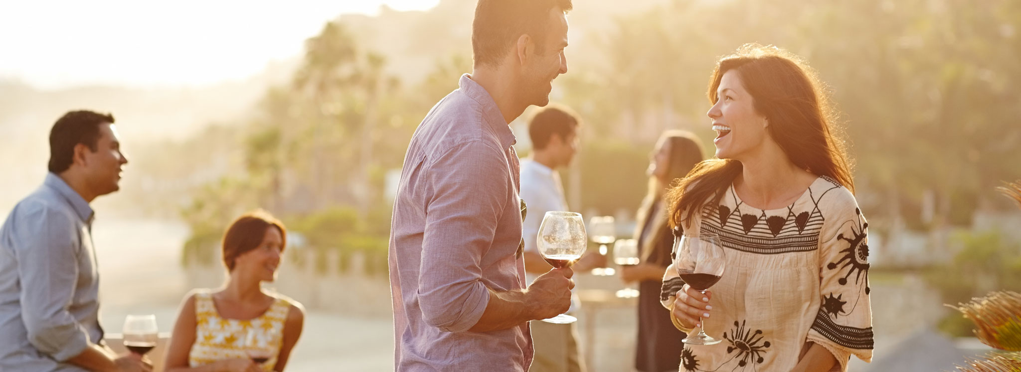 Man and woman laughing while holding glasses of wine